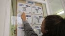 Una joven consulta un tablón de anuncios con pisos en alquiler.