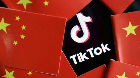 Unas banderas chinas fotografiadas al lado del logo de TikTok.