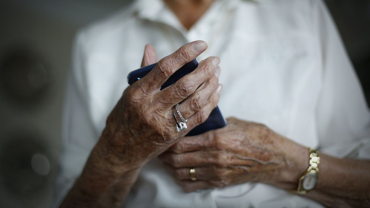 Una mujer consulta su tel�fono m�vil en una sala de aeropuerto
