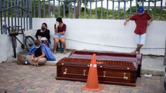 Vecinos de Guayaquil esperan al lado de dos atades colocados en plena calle, cerca de un hospital