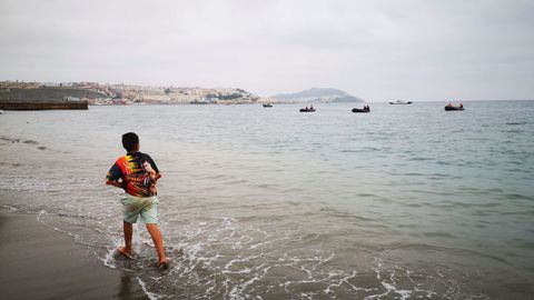 Un niño observa desde la playa de la localidad de Fnideq (Castillejos), en Marruecos, uno de los espigones de Ceuta