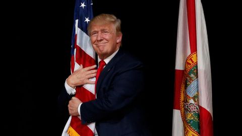 Donald Trump se abraza a la bandera de EE. UU. durante un acto celebrado en Tampa, en el estado de Florida