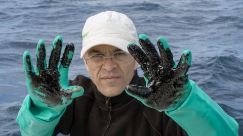 Uno de los miembros de Greenpeace que se han desplazado en un barco hasta la zona del hundimiento del Oleg Naydenov, en aguas al sur de Gran Canaria, recoge muestras del fuel