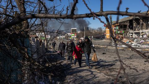 Residentes procedentes de la ciudad de Bucha, actualmente controlada por el ejército ruso, caminan con su equipaje hacia el puesto de control ucraniano, en la línea del frente en Irpin
