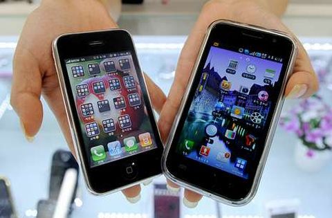 Un empleado de una tienda muestra un iPhone 3G de Apple y un Samsung Galaxy.