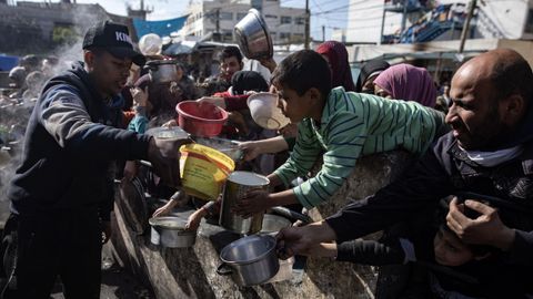 Desplazados palestinos reciben su racin de comida en Rafah.
