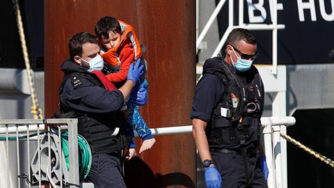Un agente carga con un niño migrante rescatado en el canal de la Mancha.