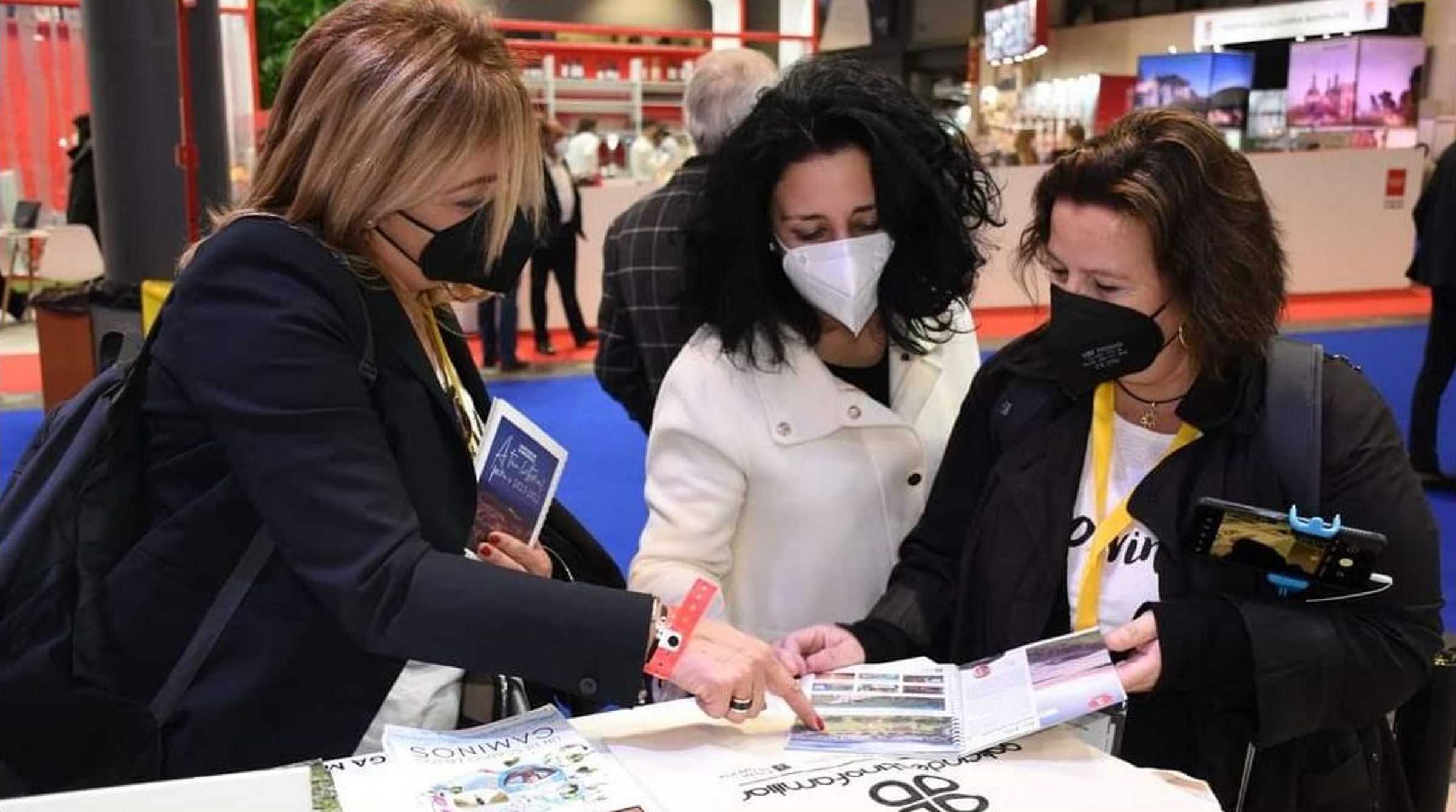 Lita Torres y Mnica Castromil muestran a la alcaldesa de Cee, en el centro, las guas de 20xVinte, en Fitur.