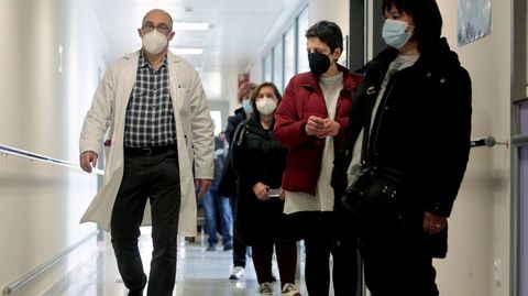 Un médico pasa junto a una fila de personas que esperan para vacunarse en el hospital de Monforte