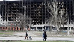 Un grupo de residentes pasan frente a un edificio destruido por los bombardeos rusos en la ciudad ucraniana de Maripol