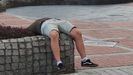 Hombre dormido en el paseo de la playa de Poniente, en Gijón