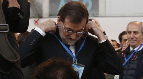 Rajoy se coloca su credencial del congreso. 