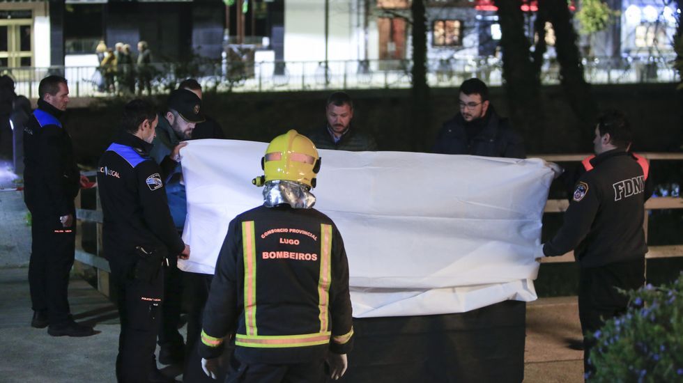 Bomberos y polic�as junto al cuerpo, tapado con una s�bana mientras lo examina la m�dico forense