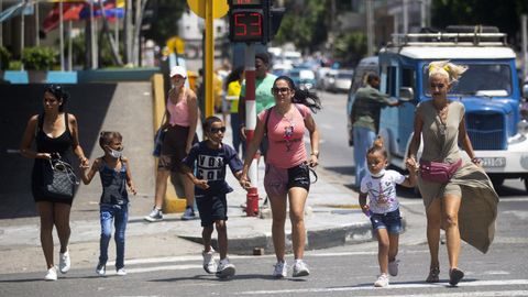 Tres madres cruzan con sus hijos de la mano un paso de peatones de La Habana