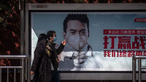 Un anuncio muestra a un hombre con mascarilla, en una calle de Pekín, China
