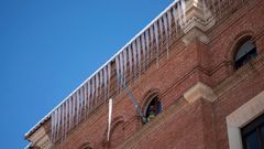 Un bombero retira carmbanos de hielo de la fachada de un edificio en Teruel