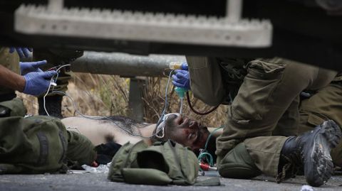 Soldados israeles tratan a un palestino vendado despus de que miembros infiltrados de las fuerzas de seguridad hebreas le dispararan.