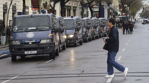 Un hombre pasa junto a las furgonetas policiales desplegadas en la Calle Goya ante las Marchas por la Dignidad