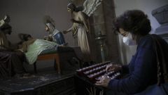 Una mujer enciende velas como ofrenda en la iglesia de San Francisco de Santiago de Compostela