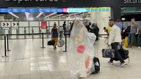 Un pasajero del aeropuerto londinense de Luton, envuelto en un plstico a modo de proteccin contra el covid