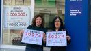 Laura (izquierda) y Mara Jos, empleadas de Loteras Galicia, en Ares, con el cartel del premio de hoy y, en la cristalera, el del 14 de diciembre