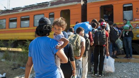 Inmigrantes se suban a un tren con destino a Serbia en la frontera entre Grecia y Macedonia, en la ciudad de Gevgelija