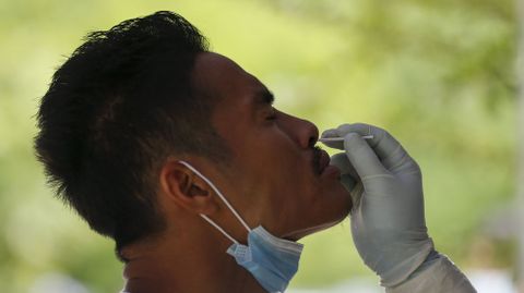 Un sanitario le toma una muestra de saliva a un jugador de fútbol en Yangon, Myanmar
