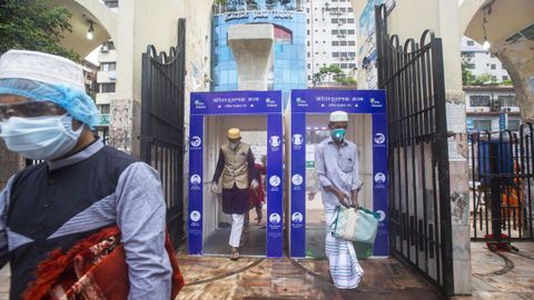 Musulmanes pasan a través de una cámara de desinfección para acceder a una mezquita en Dacca