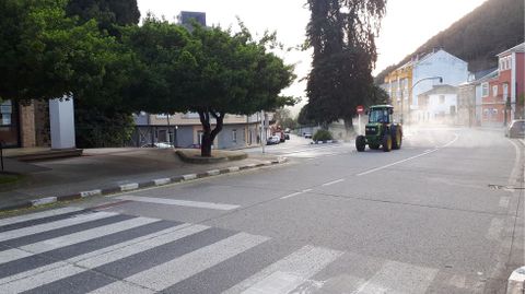 Un tractor provisto de un pulverizador desinfecta las calles de Quiroga