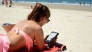 Imagen de archivo de una mujer leyendo con un libro electrnico en una playa de Vigo