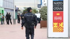 Un polica junto al cartel de la cumbre de la OTAN que se celebra en Madrid.