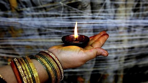 Una mujer india sujeta una vela durante un ritual religioso junto al arbol Banyan durante el festival Vat Purnima, a las afueras de Bombay (India).
