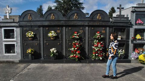 Una mujer pasa delante de unos nichos decorados con flores rojas y blancas, este 1 de noviembre en el cementerio público de Monforte