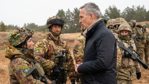 El secretario general de la OTAN, Jens Stoltenberg, junto a algunas tropas desplegadas en una base militar.