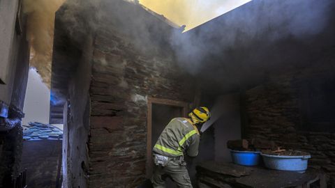 Voluntarios trabajan intentando evitar que el fuego se extienda a otra vivienda.