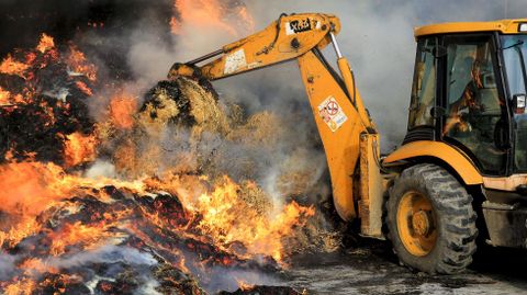 Una excavadora deshizo los montones de hierba que ardan para facilitar la extincin del fuego