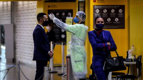 Personal de salud toma la temperatura a los que ingresan a una zona de embarque en el aeropuerto internacional de Guarulhos este lunes, en Sao Paulo (Brasil)