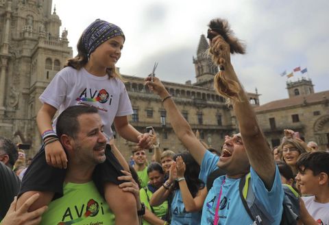 Un padre le corta el pelo a su hija a la llegada a la plaza del Obradoiro de Santiago en la peregrinacin contra el cancer infantil