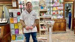 Gonza junto al puesto a favor de Down Asturias en la Farmacia Migoya, en el que vende adornos navideños y calendarios para recaudar fondos.