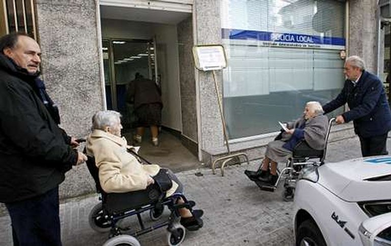 José Luis Iravedra (izquierda), empujando la silla de ruedas de una mujer para llevarla a votar.