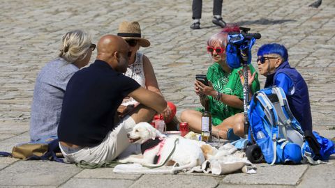Un grupo de peregrinos, comiendo y bebiendo sentados en la plaza del Obradoiro