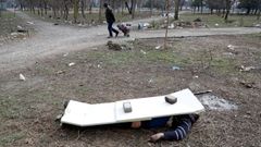 El cadver de un ucraniano muerto a causa de los bombardeos sobre Maripol, cubierto por unos tablones, en un parque de la ciudad asediada por tropas rusas y separatistas de Donetsk