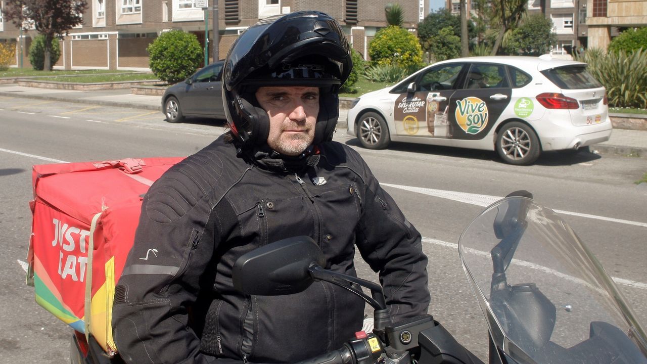 Juan Carlos, a los mandos de su motocicleta con la que reparte comida a domicilio, posa para el fot�grafo en Gij�n.
