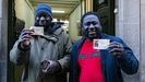 Los gambianos Modi Drame e Ibrahim Kante posan frente la administración de lotería número 1 de Olot, donde compraron cada uno un décimo del número agraciado con el segundo premio de la lotería.