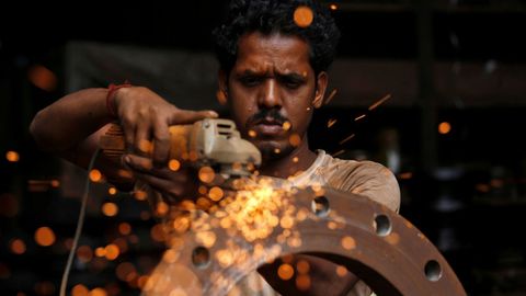 Un trabajador usa una amoladora de disco en un taller de Bombay, en India