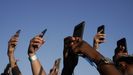 Varias personas grabando un concierto al sol con sus teléfonos móviles.