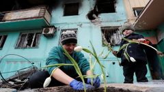 Una mujer planta tulipanes con su hija cerca de un edificio destruido tras un bombardeo ruso en Mariúpol.