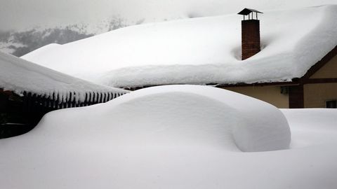 Un vehculo cubierto de nieve, en el pueblo asturiano de Pajares