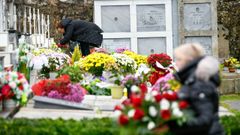 Dos mujeres colocan flores en tumbas del cementerio de Silleda