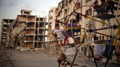 Niños palestinos disfrutan de una noria cerca de edificios residenciales, destruidos el verano pasado durante una guerra de 50 días, al norte de la Franja de Gaza